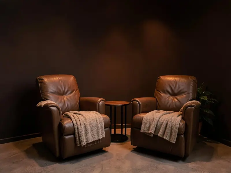 Recovery lounge with two empty leather recliners, a small side table and soft warm lighting